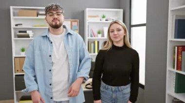 Modern ofis ortamında kolları çapraz duran kendine güvenen erkek ve kadın profesyonel takım atmosferini yansıtıyor..