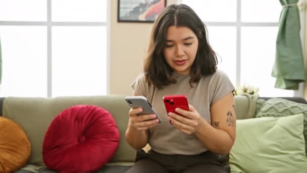 一位年轻的惊慌失措的女人在一间舒适的现代公寓客厅里检查她的智能手机 这体现了她随意的家庭生活 — 图库视频影像