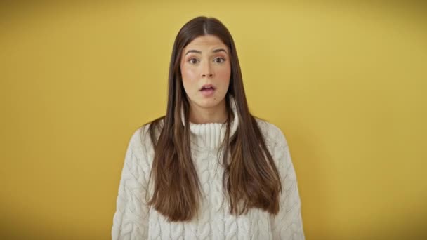 若いヒスパニック系女性が 誤って手で口を覆う美しいセーターに衝撃を受けた 単離された黄色の背景で明らかにされた秘密 — ストック動画