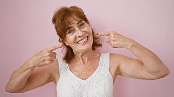 快乐的中年女性指向完美的牙齿 在粉色孤立的背景下炫耀自己的牙齿健康 — 图库视频影像