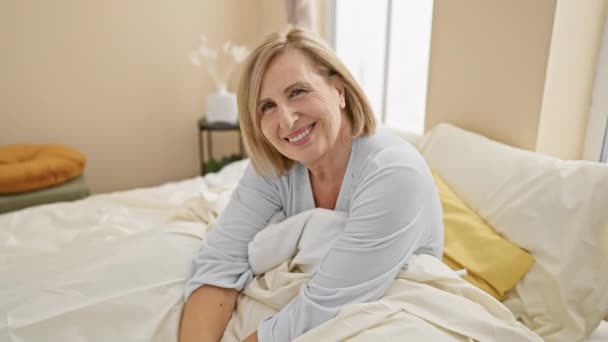 Smiling Mature Blonde Woman Relaxing Bright Bedroom Setting — Stock Video
