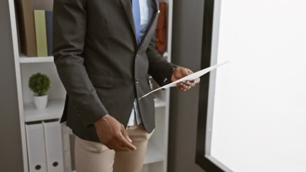 現代のオフィスの設定で文書をレビューするスーツの思慮深いアフリカの男 — ストック動画