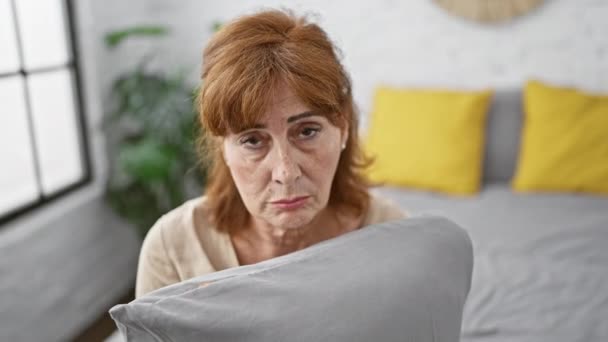 ベッドルームで苦しんでいる中年女性 彼女がベッドに座っているときのストレス 悲しみの厳粛な表現 枕を抱擁し 怒りとうつ病で泣く — ストック動画