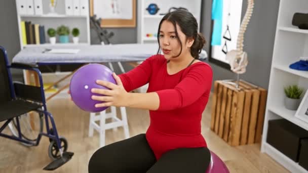Hispanic Kvinna Utövar Med Lila Boll Ett Terapirum Skildrar Fitness — Stockvideo