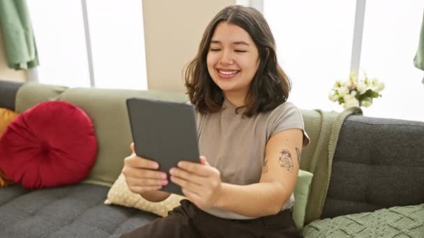 Mujer Hispana Joven Sonriendo Mientras Usa Una Tableta Sentada Sofá — Vídeos de Stock