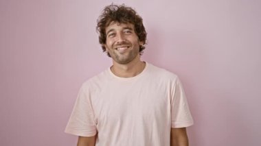 Pembe bir arka plana bakıp gülümseyen neşeli genç bir adam güven ve neşe saçar..
