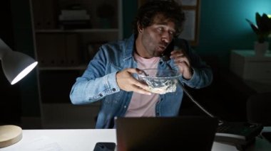 Kot ceketli İspanyol adam ofiste geç saatlere kadar çalışıyor, telefonla konuşuyor ve salata yiyor..