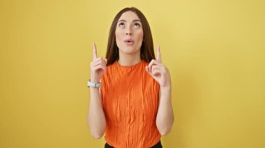 Kolsuz tişörtlü neşeli İspanyol kız yukarı bakıyor, afallamış! Bir sürü fotokopi alanı olan izole edilmiş sarı bir stüdyoda duruyoruz..