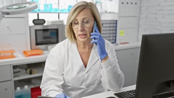 現代の研究室でタブレットを使用しながら ラボコートで話している成熟した女性科学者 — ストック動画