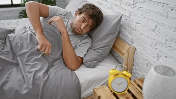 Втомлений Чоловік Лежить Ліжку Очі Закриті Помітним Будильником Мінімалістичній Спальні — стокове відео