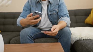 Akıllı telefon kullanan ve kapalı koltukta otururken online ödeme için kredi kartı tutan bir adam..