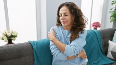 Neşeli, kendinden emin orta yaşlı İspanyol kadın evinin sıcaklığında kendini seviyor, koltukta oturuyor, ışıldayan bir gülümsemeyle kendini sevdiriyor..