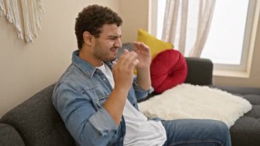 Evdeki kanepede oturan ezilmiş genç Arap adam, elleri başının üstünde, stres baş ağrısından yıpranmış. Migren ağrılarının zirvesinde ıssız bir ifade..