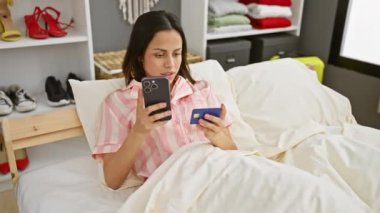 İspanyol kadın kredi kartıyla yatak odasındaki akıllı telefonu karşılaştırıyor.