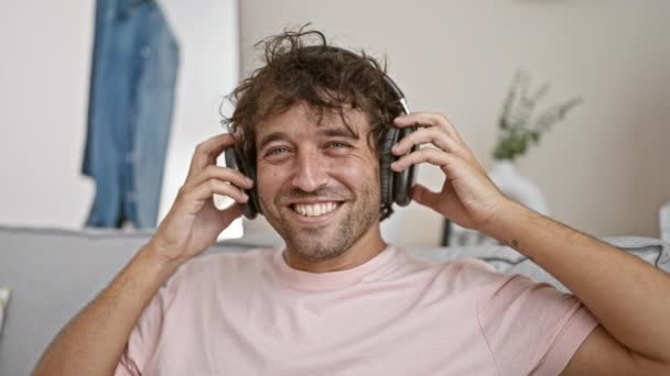 Hombre Alegre Utiliza Auriculares Una Acogedora Sala Estar Irradiando Ambiente — Vídeo de stock