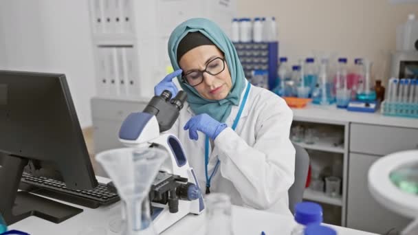 장비로 둘러싸인 실험실 환경에서 현미경을 히잡에 집중된 — 비디오