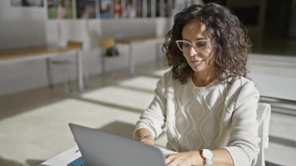 成熟したヒスパニック女性は 現代のオフィスの設定でラップトップを使用して 思慮深さと集中を表現 — ストック動画