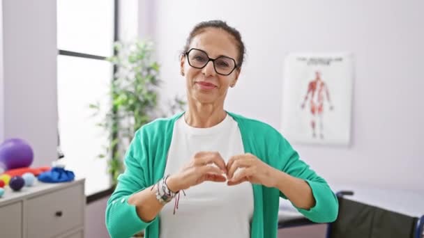 Glada Medelålders Latinamerikanska Kvinna Sjukgymnast Forma Hjärta Symbol Med Händerna — Stockvideo