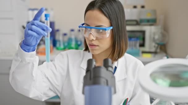 研究室では 焦点を当てた女性科学者が青い液体で試験管を検査し 医療を紹介しています — ストック動画