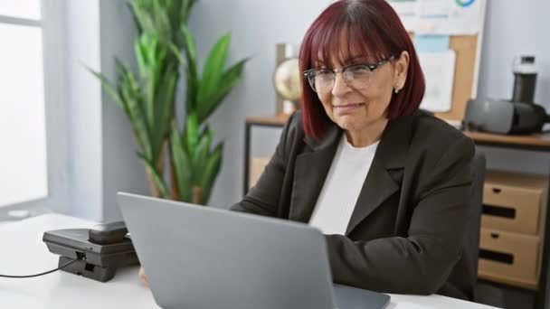 Впевнена Жінка Середнього Віку Окулярах Посміхається Працюючи Ноутбуці Сучасній Офісній — стокове відео
