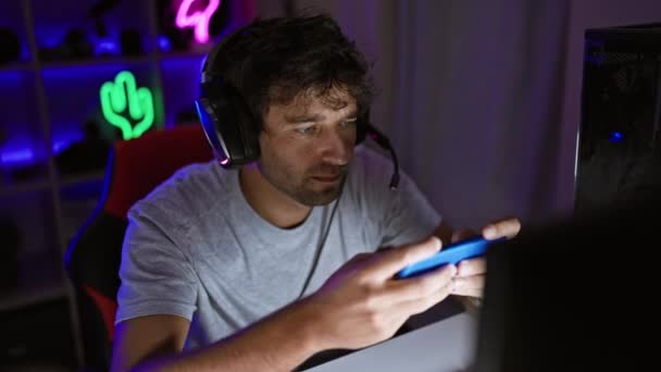 Handsome Man Beard Headphones Engages Smartphone Neon Lit Gaming Room — Stock Video