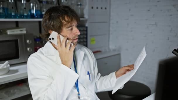 一位穿着实验室外套的专注的男性科学家在实验室里打电话时分析文书工作 — 图库视频影像
