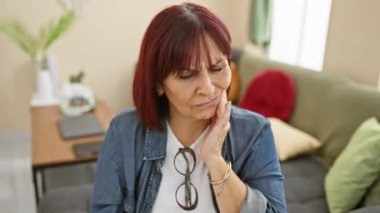 Orta yaşlı İspanyol bir kadın. Gömlek giyiyor, diş ağrısı yüzünden ağza dokunuyor. Hastalık onu rahatsız ediyor, acilen dişçiye gitmesi gerekiyor..