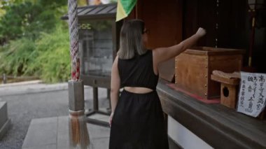 Manzaralı Kyoto anı, gözlüklü güzel İspanyol kadın Kodaiji Tapınağı 'nda zili çalmak için halat çekiyor.