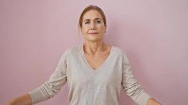 Güzel orta yaşlı sarışın kadın yogayı mutlulukla kucaklıyor, gözleri kapalı meditasyon yapıyor, izole edilmiş pembe arka planda rahatlıyor - olgun yetişkinler için sağlıklı bir yaşam tarzı konsepti