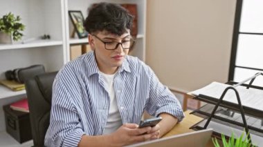 Mutlu genç bir adam modern ofis ortamında akıllı telefonuyla iyi haberleri kutlar..