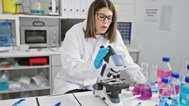 Focused Hispanic Woman Scientist Analyzing Samples Microscope Modern Laboratory Setting — Stock Video