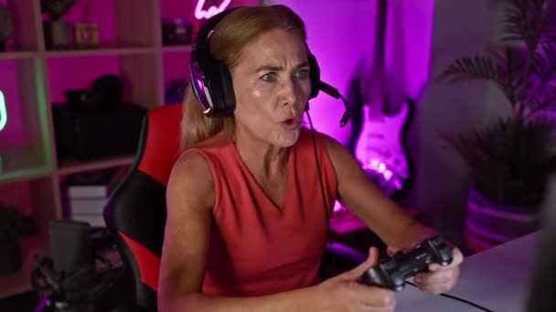 Μια Μεσήλικη Ξανθιά Γυναίκα Φαίνεται Αγχωμένη Ενώ Παίζει Βιντεοπαιχνίδια Ένα — Αρχείο Βίντεο