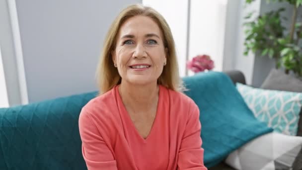 Glada Medelålders Blonda Kvinna Sitter Soffan Hemma Visar Upp Toothy — Stockvideo