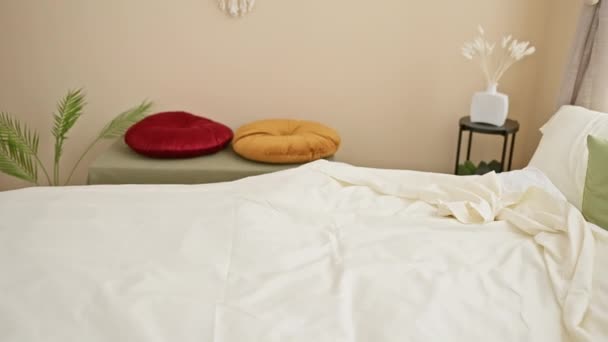 一位中年妇女在一间舒适的卧室里放松下来 卧室里有五颜六色的枕头和白色的床上用品 — 图库视频影像