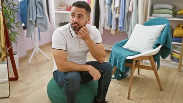 Pohledný Hispánec Sedí Zamyšleně Stylové Šatně Obklopen Módní Oblečení — Stock video