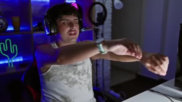 ヘッドフォン付きネオンライトゲームルームでタンクトップダンスの若い男 — ストック動画