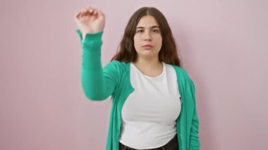 Küstah, genç İspanyol kadın daha fazla el kol hareketi yapmasın! Güzel yüzüne kazınmış ciddi ve olumsuz bir ifade izole edilmiş pembe bir duvara kazınmış..