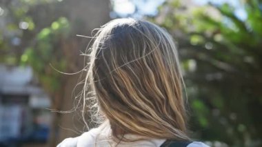 Dalgın genç bir kadın yemyeşil bir parkın içinde güneşli bir günün tadını çıkarıyor..