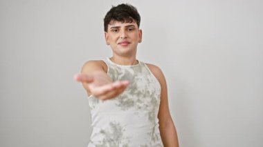 Kolsuz tişörtlü arkadaş canlısı genç bir adam, yardım ve kabul jesti içinde içi boş bir avuç sunuyor, beyaz arka planda neşeli bir gülümsemeyle duruyor, pozitif lgbtq desteğinin sembolü.