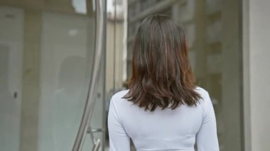 Kendine güvenen genç bir İspanyol kadın şehir ortamında poz veriyor, arkasında da yumuşak odaklı şehir hayatı..