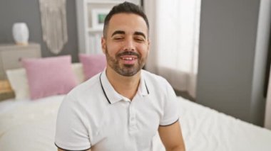 Neşeli, genç İspanyol bir adam kameraya göz kırparken yakalandı. Yatak odasında seksi bir gülümsemeyle oturuyor.
