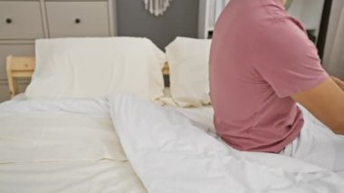 Genç İspanyol bir adam modern bir yatak odasında tek başına rahatlıyor, sükunet ve zarafet dolu bir hava yayıyor..