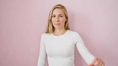 Kendine güvenen genç sarışın kadın parmaklarıyla küçük boy işareti yapıyor, izole edilmiş pembe arka planda duruyor. şirin küçük ölçü kavramı.