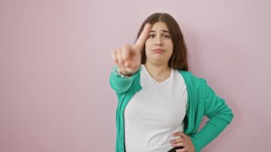 Ateşli, genç İspanyol kadın sert bir uyarıda bulunuyor. İzole edilmiş pembe arka planda hiçbir işaret yok. Yüz ifadesi 