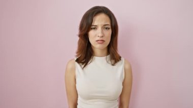 Uykulu gözlü, kolsuz tişörtlü, güzel İspanyol bir kadın, uyanıyor, yorgun ama akşamdan kalma, izole pembe arka planda biraz dağınık görünüyor..