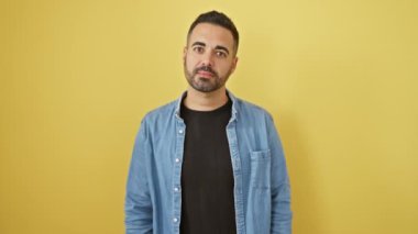 Tüh! Kot gömlekli genç İspanyol adam pişmanlıktan kafasını vuruyor. Bir şey unuttum, bir hata yaptım! Kötü hatıralar, sarı, izole bir arka plana karşı bilgisiz kalmalar.