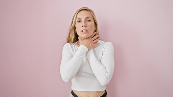 痛みの若いブロンドの女性 窒息と窒息 単離されたピンクの背景上の奇妙な試みによる窒息 重度の健康問題 — ストック動画