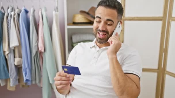 Uśmiechnięty Hiszpan Trzymający Kartę Kredytową Rozmawiający Przez Telefon Dobrze Zorganizowanej — Wideo stockowe