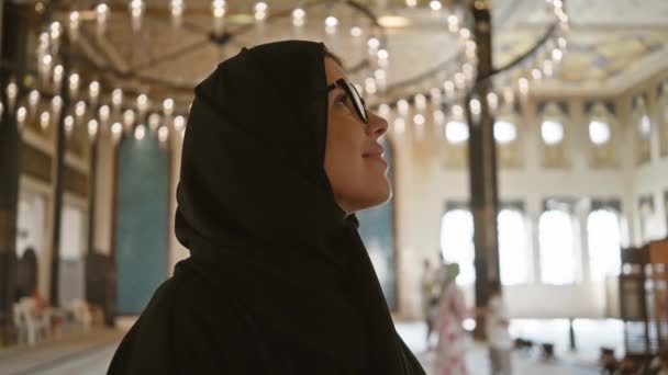 一个戴眼镜 头戴头巾 面带微笑的女人出现在鞑靼卡塔拉文化村清真寺华丽的建筑中 — 图库视频影像