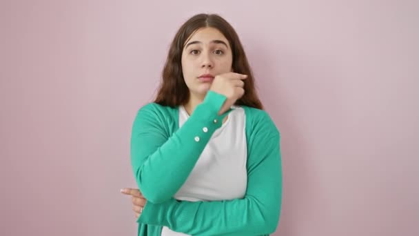 隠された秘密 ピンクのセーターの若く美しいヒスパニック女性 ジッピングリップシャット ミュート陰謀の孤立した背景上の指のジェスチャー — ストック動画
